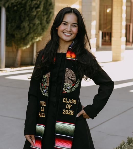 Joy Ok smiles and poses for the camera in a graduate stole.