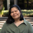 Ana Castellon is pictured in a green long sleeve shirt with a natural background.